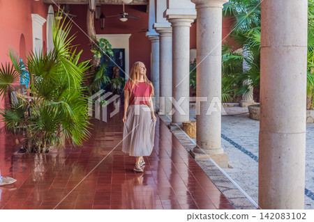 Female tourist walks and twirls through colonial arches, tiled floors and stone details, showing Mexico travel, culture and elegant vacation style concept Female tourist walks and twirls through colonial arches, tiled floors and stone details, showing Mexico travel, culture and elegant vacation style concept 142083102