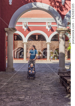 Man walking with baby stroller through Mexican colonial street, colorful architecture, heritage courtyard, fatherhood and family travel with baby concept Man walking with baby stroller through Mexican colonial street, colorful architecture, heritage courtyard, fatherhood and family travel with baby concept 142083105