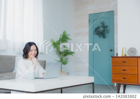 A young woman looking at a computer in the living room A young woman looking at a computer in the living room 142083802