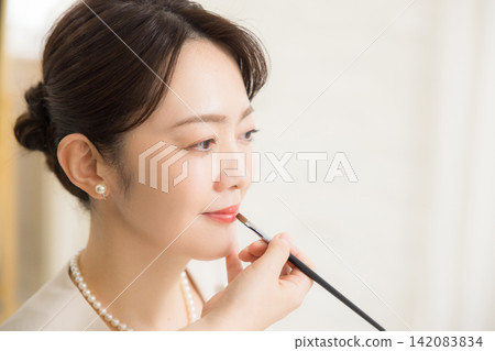 一位女士正在美容院做頭髮和化妝。 142083834