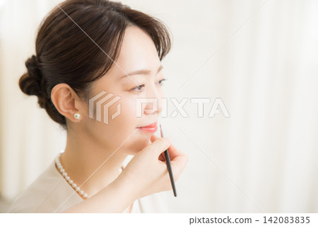 一位女士正在美容院做頭髮和化妝。 一位女士正在美容院做頭髮和化妝。 142083835