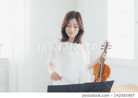 一位女士在家練習小提琴。 一位女士在家練習小提琴。 142083997
