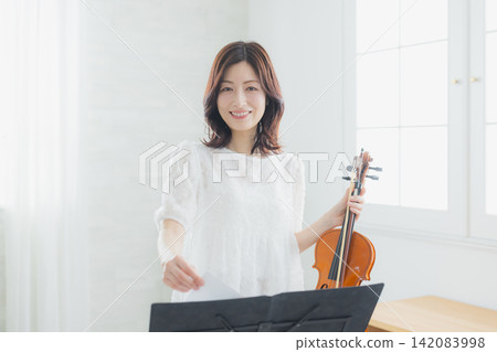 A woman practicing the violin at home. A woman practicing the violin at home. 142083998
