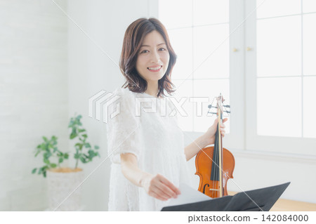 一位女士在家練習小提琴。 一位女士在家練習小提琴。 142084000