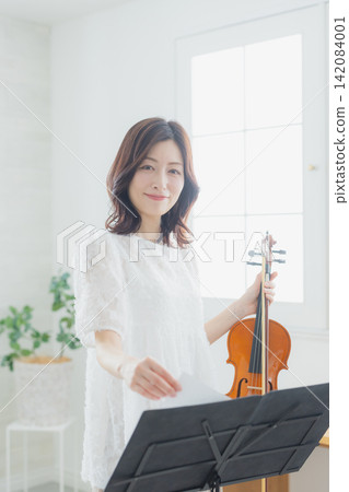 A woman practicing the violin at home. A woman practicing the violin at home. 142084001