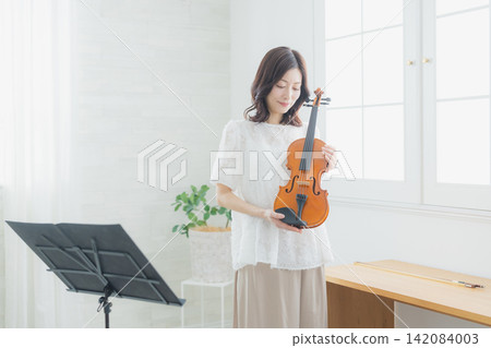 A woman practicing the violin at home. A woman practicing the violin at home. 142084003