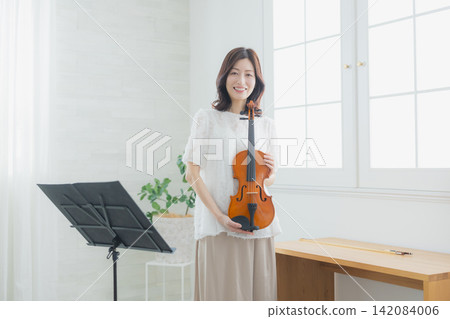 一位女士在家練習小提琴。 一位女士在家練習小提琴。 142084006