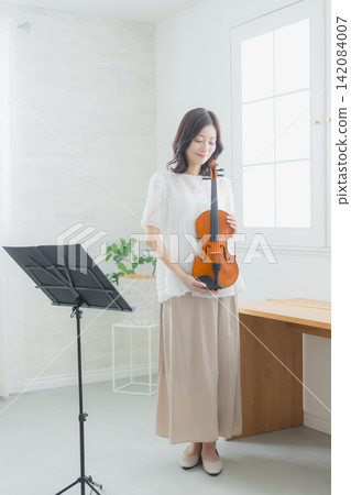A woman practicing the violin at home. A woman practicing the violin at home. 142084007