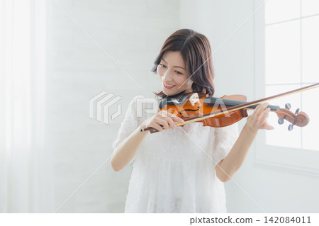 一位女士在家練習小提琴。 一位女士在家練習小提琴。 142084011