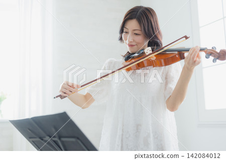 一位女士在家練習小提琴。 一位女士在家練習小提琴。 142084012