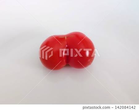 Unusually shaped red cherry tomatoes placed on a white plate Unusually shaped red cherry tomatoes placed on a white plate 142084142