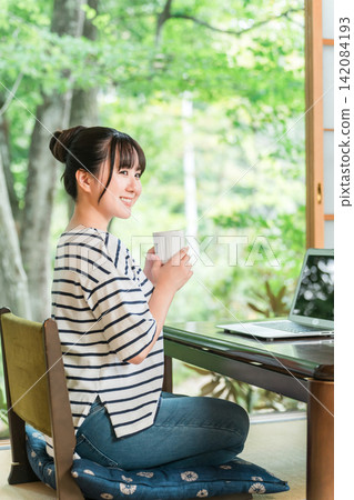 一位自由職業婦女在工作假期中休息，在住處工作，並在休息時間喝咖啡。 142084193
