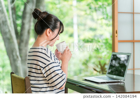 一位自由職業婦女在工作假期中休息，在住處工作，並在休息時間喝咖啡。 142084194