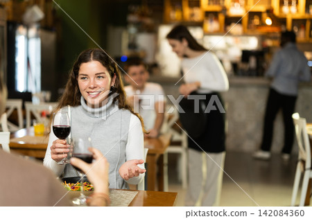 Girl in cafe sits opposite male companion, has nice conversation Girl in cafe sits opposite male companion, has nice conversation 142084360