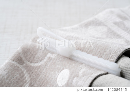 Close-up of a curtain hook (adjustable type) attached to a curtain. 142084545