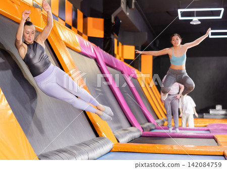 Adult woman trains jumping in trampoline center Adult woman trains jumping in trampoline center 142084759