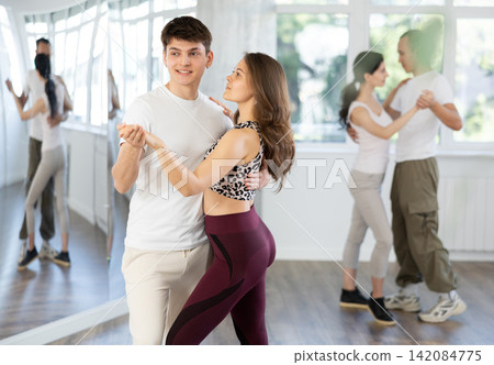 Dance studio - students in casual clothes learn to dance tango Dance studio - students in casual clothes learn to dance tango 142084775