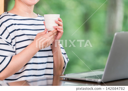 一位自由職業婦女在工作假期中休息,在住處工作,並在休息時間喝咖啡。 一位自由職業婦女在工作假期中休息,在住處工作,並在休息時間喝咖啡。 142084782