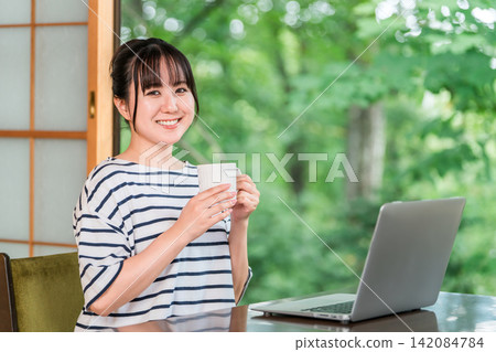 一位自由職業婦女在工作假期中休息，在住處工作，並在休息時間喝咖啡。 142084784