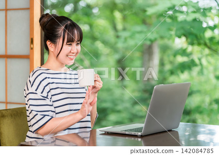 一位自由職業婦女在工作假期中休息，在住處工作，並在休息時間喝咖啡。 142084785