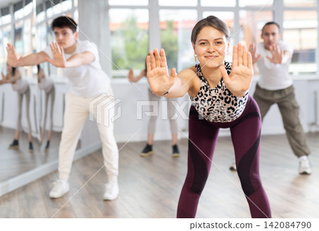 Group of women and men enjoying active dance movement in modern studio Group of women and men enjoying active dance movement in modern studio 142084790