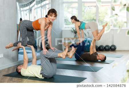 Studio couples practicing yoga with partner. Balancing and meditation for two Studio couples practicing yoga with partner. Balancing and meditation for two 142084876