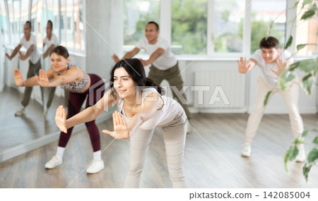 Young brunette warming up with group in dance class 142085004
