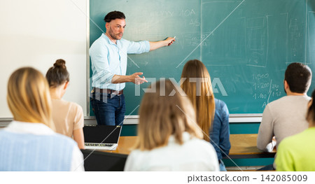 Male teacher giving presentation for students in lecture hall Male teacher giving presentation for students in lecture hall 142085009