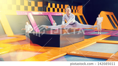 Emotive adult woman having great time while jumping on colorful trampoline in entertainment center Emotive adult woman having great time while jumping on colorful trampoline in entertainment center 142085011