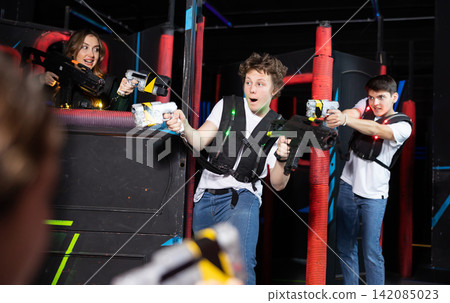 Two guys and one girl running and dodging while playing lasertag Two guys and one girl running and dodging while playing lasertag 142085023