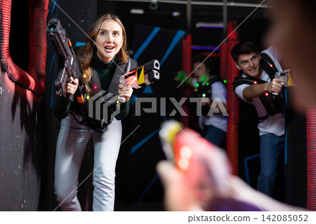 Girl running and dodging while playing lasertag 142085052