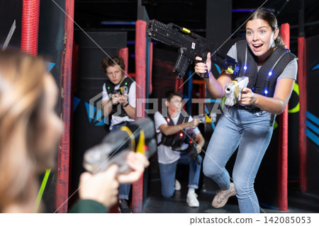Girl running and dodging while playing lasertag Girl running and dodging while playing lasertag 142085053