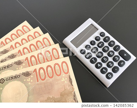五張面值10000日元的鈔票和一個白色計算器(黑色背景) 五張面值10000日元的鈔票和一個白色計算器(黑色背景) 142085362