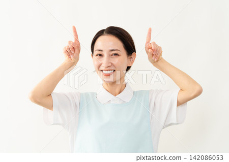 A woman wearing a light blue apron; a caregiver image. A woman wearing a light blue apron; a caregiver image. 142086053