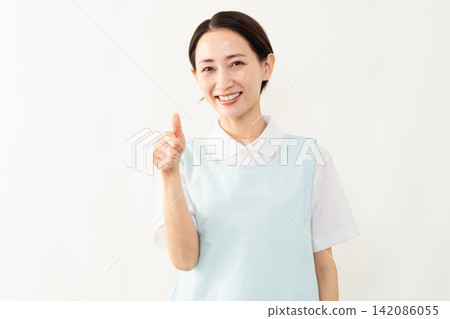 A woman wearing a light blue apron; a caregiver image. A woman wearing a light blue apron; a caregiver image. 142086055