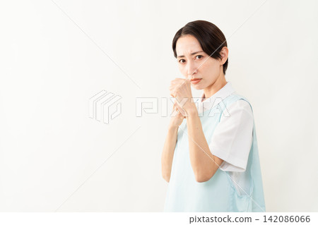 A woman wearing a light blue apron; a caregiver image. A woman wearing a light blue apron; a caregiver image. 142086066