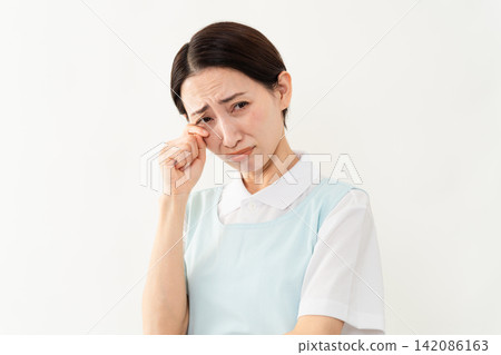 A woman wearing a light blue apron; a caregiver image. A woman wearing a light blue apron; a caregiver image. 142086163