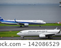 ANA and JAL aircraft passing each other on the runway at Haneda Airport. 142086529