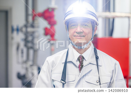 A senior male worker uses a tablet to inspect equipment in the boiler room. A senior male worker uses a tablet to inspect equipment in the boiler room. 142086910