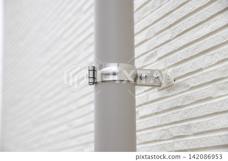 The exterior siding and drain pipes are secured with metal fittings. 142086953