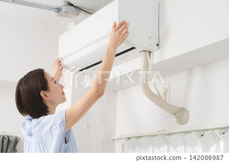 Young woman cleaning air conditioner filters Lifestyle image Young woman cleaning air conditioner filters Lifestyle image 142086987