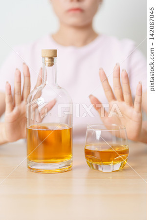 woman making stop hand gesture to refuse a glass of whiskey, Healthy man say no to alcohol drink, stop alcoholism and addiction concept. Responsible man reject a drink before driving and quit booze woman making stop hand gesture to refuse a glass of whiskey, Healthy man say no to alcohol drink, stop alcoholism and addiction concept. Responsible man reject a drink before driving and quit booze 142087046