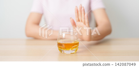 woman making stop hand gesture to refuse a glass of whiskey, Healthy man say no to alcohol drink, stop alcoholism and addiction concept. Responsible man reject a drink before driving and quit booze 142087049