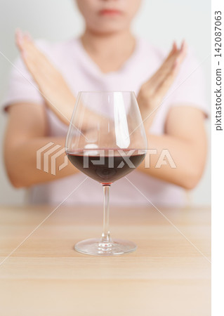 woman making stop hand gesture to refuse a glass of Wine, Healthy man say no to alcohol drink, stop alcoholism and addiction concept. Responsible man reject a drink before driving and quit booze woman making stop hand gesture to refuse a glass of Wine, Healthy man say no to alcohol drink, stop alcoholism and addiction concept. Responsible man reject a drink before driving and quit booze 142087063