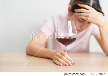 Stressed woman drinking Wine alone with problem. Exhausted drunk woman looking stressed and sleepy. Alcohol addiction, Alcoholism, emotional distress and mental health concept Stressed woman drinking Wine alone with problem. Exhausted drunk woman looking stressed and sleepy. Alcohol addiction, Alcoholism, emotional distress and mental health concept 142087064