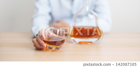 man with glass of cognac on table, suffering from alcohol addiction and alcoholism concept. depicting emotional distress, depression, substance abuse problem, unhealthy lifestyle and mental health man with glass of cognac on table, suffering from alcohol addiction and alcoholism concept. depicting emotional distress, depression, substance abuse problem, unhealthy lifestyle and mental health 142087105