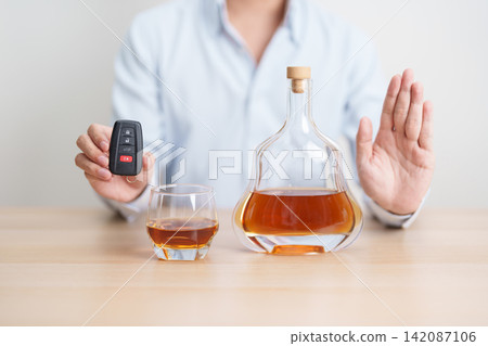 Responsible man reject a drink before driving for road safety, Man making stop hand gesture to refuse a glass of whiskey and car remote. Avoid drink and drive, Drunk Driving Law concept Responsible man reject a drink before driving for road safety, Man making stop hand gesture to refuse a glass of whiskey and car remote. Avoid drink and drive, Drunk Driving Law concept 142087106