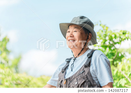一位身著戶外服飾的老者置身於鬱鬱蔥蔥的森林中。 142087217