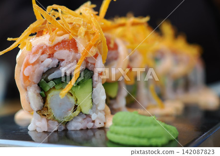 Sushi roll with avocado and seafood served on a black plate Sushi roll with avocado and seafood served on a black plate 142087823
