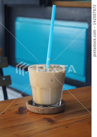 Iced coffee served in a glass on a wooden table Iced coffee served in a glass on a wooden table 142087872